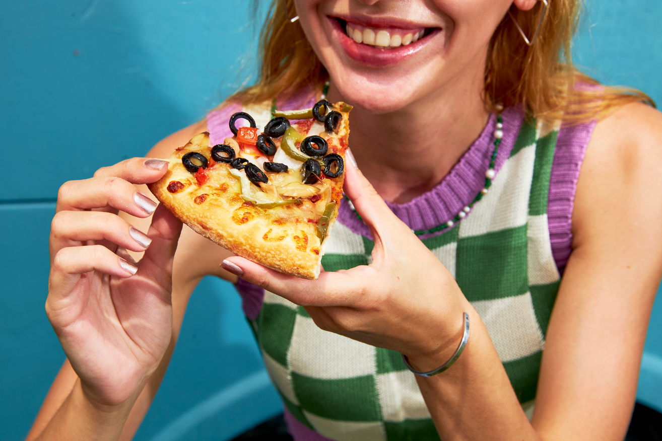 Woman Enjoying a Slice of Plant-Based Pizza